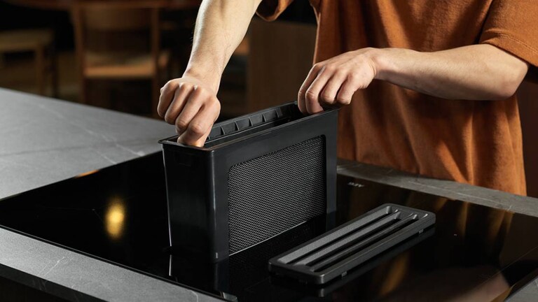 Ruka vkládající filtr do odsavače par