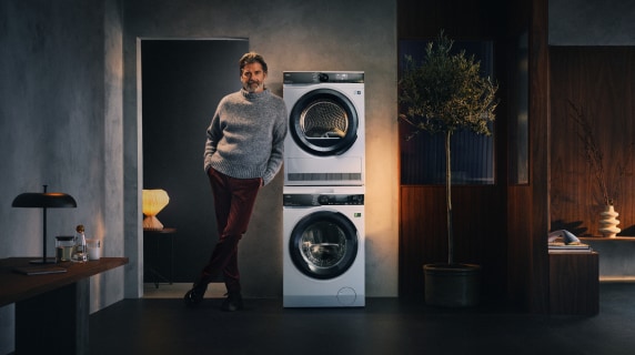 Muž ve svetru vedle pračky a sušičky